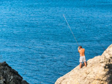 Sudak, Kırım Cumhuriyeti - 17 Eylül 2020: Olta kamışlı bir balıkçı. Mavi Karadeniz