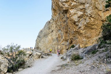 Sudak, Kırım Cumhuriyeti - 17 Eylül 2020: yüksek bir uçurum çıkıntısı altındaki insanlar. Alchak Burnu. Karadeniz kıyısı