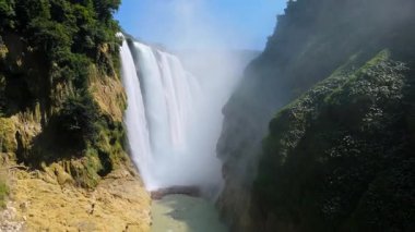 Cascada de Tamul tropikal bitkilerle çevrili yüksek bir uçurumdan düşen güçlü su gösteriyor. İnsanlar bu doğal alanın güzelliğini San Luis Potosi, Meksika 'da yaşıyorlar..