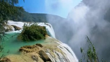 Cascada de Tamul tropikal bitkilerle çevrili yüksek bir uçurumdan düşen güçlü su gösteriyor. İnsanlar bu doğal alanın güzelliğini San Luis Potosi, Meksika 'da yaşıyorlar..