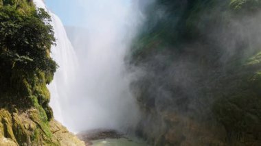 Cascada de Tamul tropikal bitkilerle çevrili yüksek bir uçurumdan düşen güçlü su gösteriyor. İnsanlar bu doğal alanın güzelliğini San Luis Potosi, Meksika 'da yaşıyorlar..