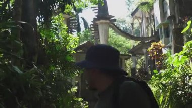 Ziyaretçiler Xilitla 'daki Castillo de Edward James bahçelerinde yürüyorlar. Güneş, yemyeşil bitkiler ve yapılar arasında ışık ve gölgelerle desenler yaratır..