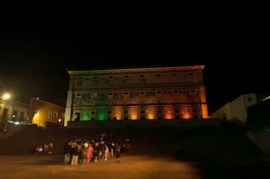 Alhondiga de Granaditas yakınlarındaki birçok insan, Meksika 'nın Guanajuato kentindeki binayı renkli ışıklarla aydınlatırken sırada bekliyor. Toplantı, toplumsal çatışmayı gösteriyor..