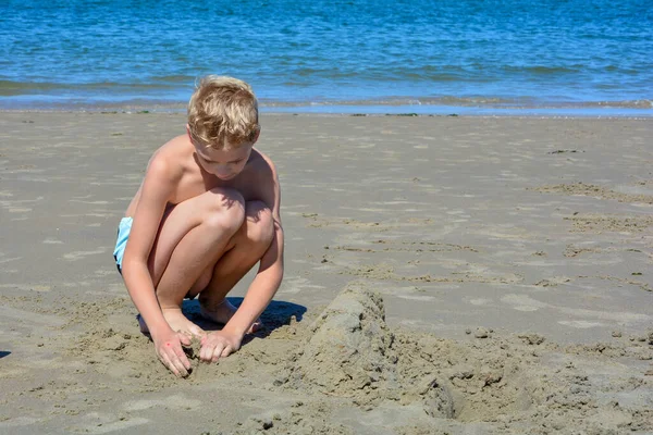 Niño Rubio Con Bañador Construye Castillo Arena Arena Playa Frente —  Fotos de Stock