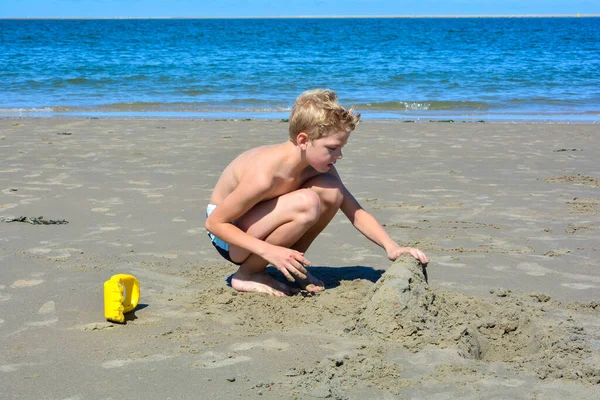 Malý Blonďatý Chlapec Plaveckými Trenýrkami Staví Hrad Písku Pláži Před — Stock fotografie