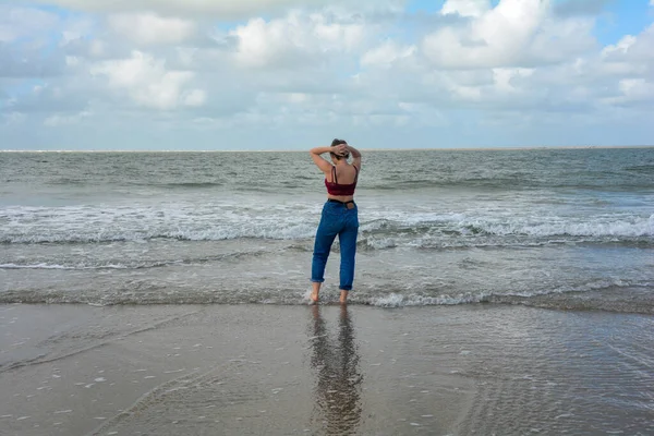 Młoda Dziewczyna Dżinsach Krótki Top Stoi Boso Falach Piaszczystej Plaży — Zdjęcie stockowe