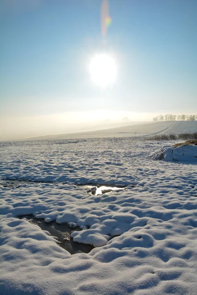 Landscape with a lot of snow, fields ,frozen spots, sun and   Dung heap in Bavaria, Germany