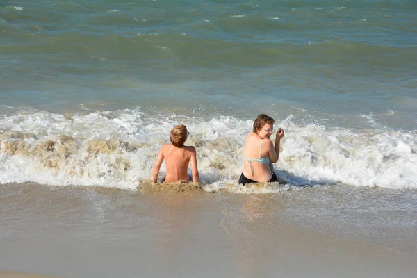 Dwoje Dzieci Siedzi Pełne Radości Piaszczystej Plaży Środku Fal Nad — Zdjęcie stockowe