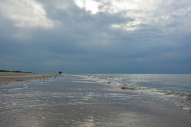 Kuzey Denizi kıyısında bulutlu gökyüzü olan kumlu bir sahilde akşam yürüyüşü