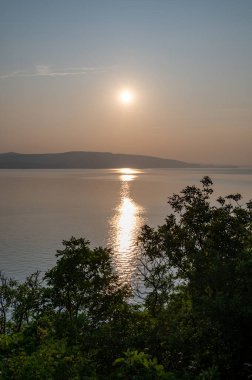 Hırvatistan, Avrupa 'da denizde gün batımı, arka planda Krk adası ve önde ağaçlar