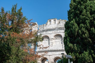 Türünün en büyük altıncı amfitiyatrosu olan Pula Arena 'nın bir kısmı, Hırvatistan ve Avrupa' da yeşil ağaçlar ve mavi bir gökyüzü bulunuyor.