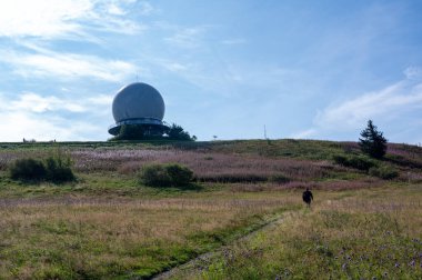 Radar kubbesi, Almanya 'nın yüksek Rhoen bölgesindeki Wasserkuppe' nin zirvesinde, yeşil bir çayır ve pembe bir Willonerb ile, güzel bir yaz günü bir yürüyüşçüyle