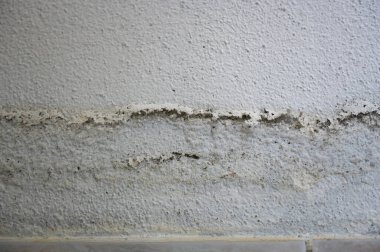 Bir dairedeki su borusunun patlamasının ardından su sızıntısı ve rutubetli bantlı hasarlı açık renkli ev duvarı