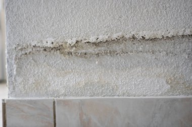 Bir dairedeki su borusunun patlamasının ardından su sızıntısı ve rutubetli bantlı hasarlı açık renkli ev duvarı