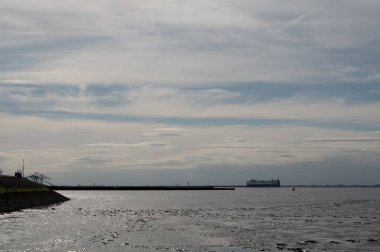 Kuzey Denizi kıyısı alçak gelgitte, ön planda çamurlu düzlükler, Bremerhaven, Almanya 'dan ayrılan konteynır gemisi, arka planda