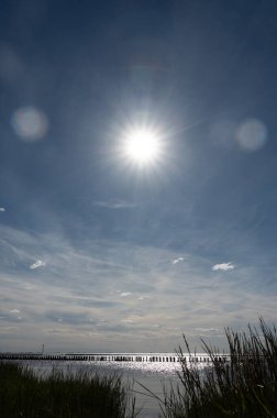 Ön planda yeşil çimenler, arka planda Kuzey Denizi 'nde dalgalar, parlak güneş ışığı ve mavi gökyüzü..