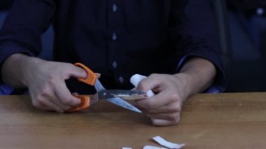 Genç adam elindeki, parmağındaki ya da küçük kesiklerdeki yaralar için yamalar kesiyor. Hemşire parmağı daha iyi kavramak için bantları şeritlere ayırır. Video çekimi Full HD 60 fps.