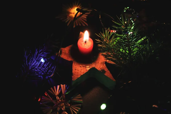 小烛台与红色的蜡烛和温暖的火焰 创造了一个神奇而和平的气氛在圣诞节 围绕着它的五彩缤纷的灯光装饰着树 — 图库照片