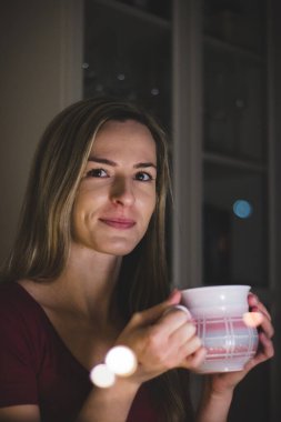 Pencereden sevgilisine meydan okuyarak bakıyor. Güzel bir sarışın, sevdiği kişiyi yemek masasında bekliyor. Avrupalı bir kadının büyüleyici ifadesi. Sıcak çay içiyorum..