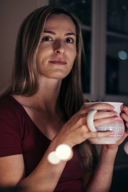 Masada oturan kahverengi gözlü güzel bir sarışının portresi. Kız, donmuş ellerini bir kupa sıcak çayla ısıtarak pencereden dışarı bakıyor. Hayatındaki küçük bir gülümseme.