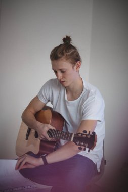 Atletik fiziği olan bir adam bir tabureye oturur ve uygun şarkıyı seçmek için ilahi kitabının sayfalarını çevirir. Elinde akustik bir gitar tutuyor. Öğleden sonra müzik karantina altında.