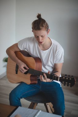 Bir öğleden sonra şarkı söylerken ve gitar çalarken odaklanmış genç bir şarkıcı. Günlük aktivitelerde olan bir adamın ortak bir portresi. Gitar çalan 20-29 yaşlarında bir çocuk..