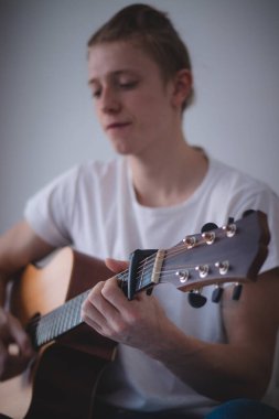 Akustik gitar çalarken yakın plan çekimler. Bir adam uygun tekniğe odaklanır. Müzik aleti çalma alıştırması yapıyorum. Boş zamanlarını harcıyorsun..