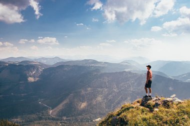 Vahşi Avusturya doğasında enerji yükleme. Kep ve kırmızı elastik hileyle daha hafif figürlü sporcu kayanın kenarında duruyor ve rahatlama ve özgürlük hissinden hoşlanıyor. Otscher Dağı Fethediliyor.