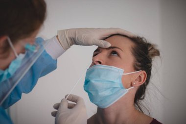 Özel bir toplama merkezinde koronavirüse karşı yapılan test için mukus toplanırken koruyucu giysi ve kalkan giymiş bir doktorun çalışmalarının ayrıntıları. Laboratuvar çalışması