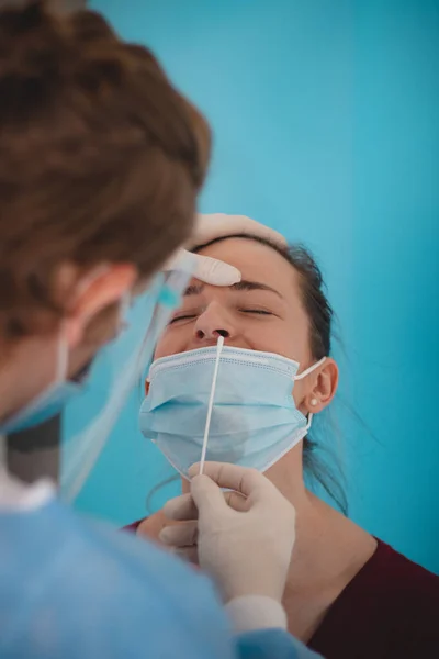 Doctor is testing for coronavirus. A young lady is waiting for a swab from the nose. Collection center. Global pandemic. Unpleasant nose skewers.