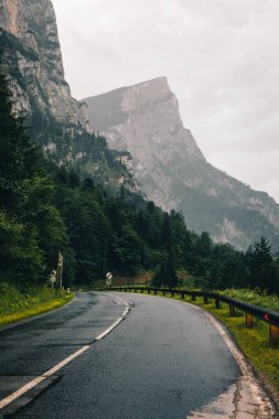 Gesause Ulusal Parkı 'nda akan uçsuz bucaksız yol keskin dağların zirvelerini ve Stockmauer, Planspitze ve daha fazlasını görmeyi vaat ediyor. Yağmurda asfalt yol. Avusturya doğası.