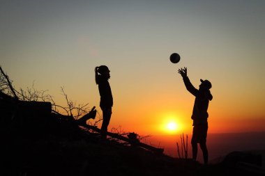 Genç bir çift gün batımında bir dağın tepesinde voleybol oynuyor ve köpekleri itaatkar bir şekilde onları bekliyor. Voleybol vuruşu. Beskydy, Czech Cumhuriyeti 'nden geçerken.