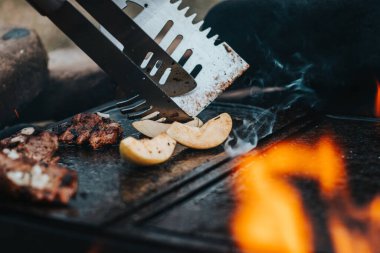 Muhteşem kokulu ve çıtır çıtır domuz boynu açık ateşte granit bir taşın üzerinde hazırlanır. Sonra, bir adam ana yemek için fırında elma hazırlar. Açık hava koltuğu. Tente, kamp..