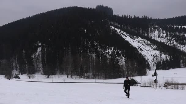 身穿黑色运动服的人拿着户外的杆子在雪地里爬行 欣赏山谷的美景 冬季徒步旅行别斯基底山体验历险 — 图库视频影像