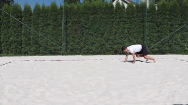 Siyah saçlı, kaslı bir sporcu, voleybol sahasındaki maçtan önce ısınıyor. Bir atlet ayı yürüyüşünü gösteriyor