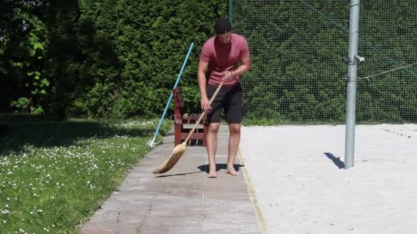 Hausmeister Roten Hemd Räumt Mit Einem Besen Sand Vom Gehweg — Stockvideo