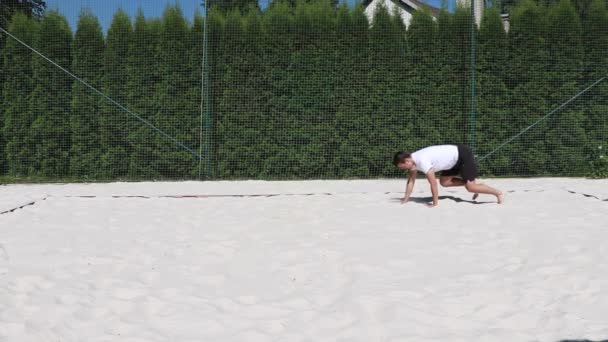 在沙滩排球场上的一场比赛之前 黑头发 体态瘦弱的运动员都在热身 一位运动员展示了熊的行走方式 — 图库视频影像