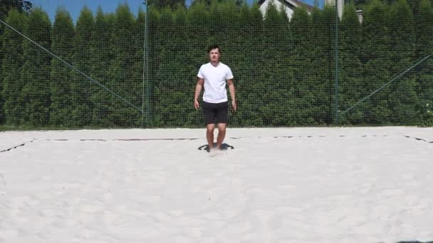 在阳光明媚的情况下 年轻的教练在沙滩排球场地上正确地执行跳跃千斤顶 — 图库视频影像