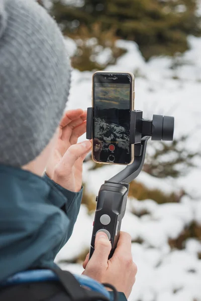 young yutuber vlogs on his social networks using a mobile phone and a gimbal for better video. Winter recording. Athlete. Detail on video transmission. Video settings.