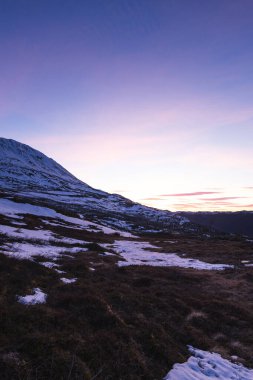 Norveç, Rjukan yakınlarındaki Gaustatoppen Dağı 'nda akşam ışığı parlıyor. Kar yamaçları ve turuncu gökyüzü sakin, görkemli bir İskandinav doğası yaratıyor..