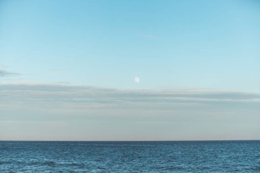 Danimarka, Skagen yakınlarındaki Kuzey Denizi 'nin sakin sularında dolunay yükseliyor. Minimalist İskandinav deniz manzarası yumuşak mavi ışıkla yıkandı.