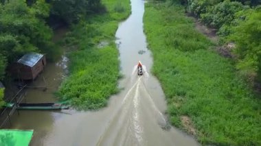 Tropikal mangrov ormanları boyunca nehirlerde yüzen teknelerin hava görüntüsü, güzel bir mangrov ormanındaki bir kanalda yelken açan bir balıkçı teknesi. Asya. Sinematik hava görüntüsü