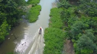 Tropikal mangrov ormanları boyunca nehirlerde yüzen teknelerin hava görüntüsü, güzel bir mangrov ormanındaki bir kanalda yelken açan bir balıkçı teknesi. Asya. Sinematik hava görüntüsü