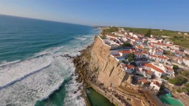 Lizbon, Portekiz yakınlarında yüksek drone manzaralı bir sahil. Kuma çizilmiş araç izleri yumuşak Atlantik dalgalarıyla karşılaşıyor. Hava görüntüleri karayla deniz arasındaki doğal desenleri ve kontrastı gösteriyor..