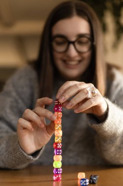 Gülümseyen ve bir zar piramidi inşa eden genç bir kadın. Sabır, odaklanma ve başarı kavramı.