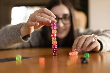 Genç bir kadının önünde masaya düşüp etrafa saçılan renkli zarlar. Eğlence ve dinamik oyun konsepti.