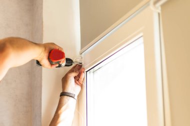 Pencere çerçevesindeki paten panjurları için işçiler mekanizmalar ve parantezler kuruyor.