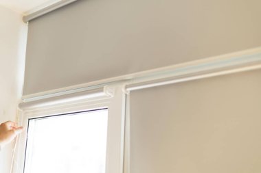 Açık gri jaluzileri pencerenin içine kurma işlemi.