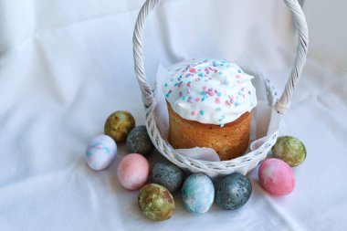 Ortodoks Paskalya Kulich 'i renkli renkli yumurtalarla dolu beyaz bir hasır sepete yerleştirdik. Geleneksel şenlikli natürmort.
