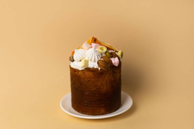 Üstünde çıtır fındık ve tatlı şekerlemeler olan ev yapımı Paskalya ekmeği. Pastel şeftali arkaplanı üzerine minimum kompozisyon.